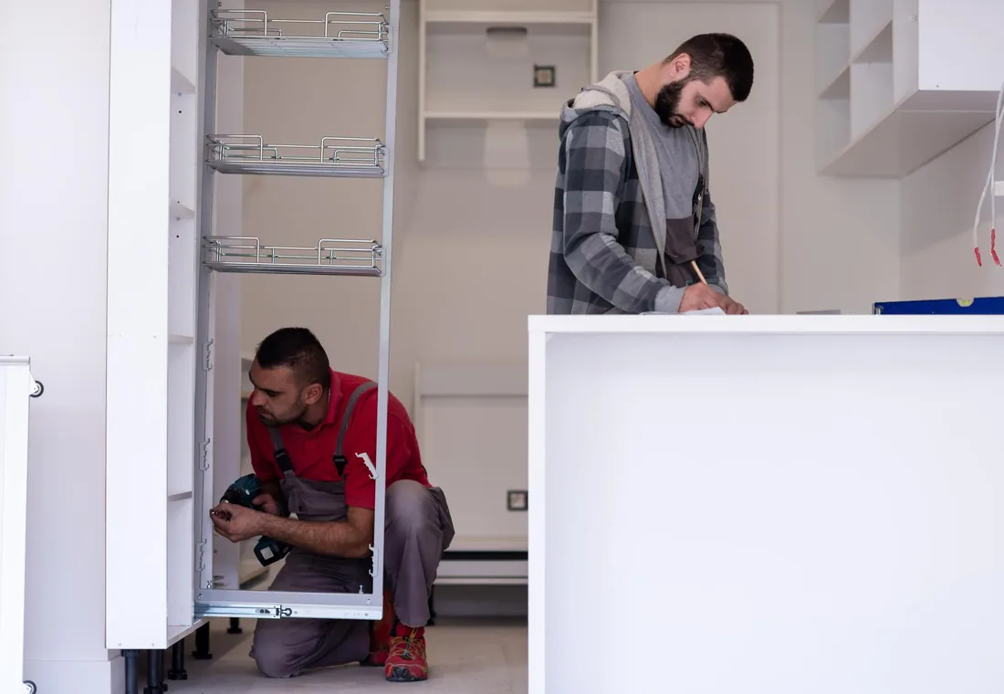 Technicians working on a built-in refrigerator